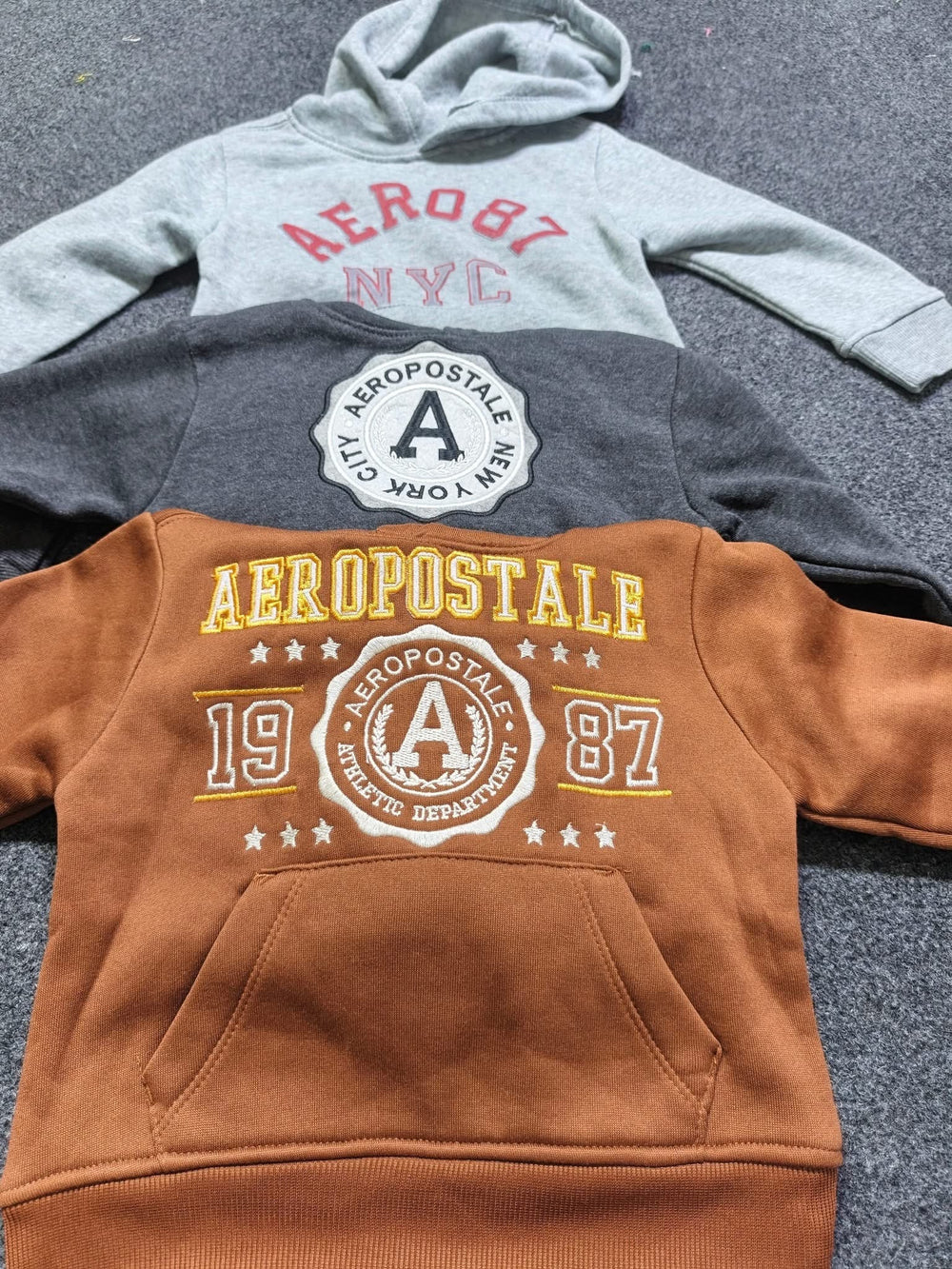 Three graphic hoodies laid out in a row
